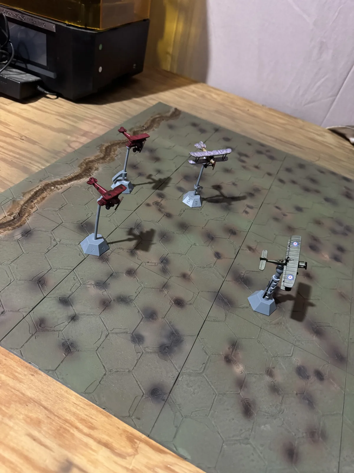 Four painted Death Spiral aircraft flying over the finished green Death Spiral Battlefield on HexAxis stands