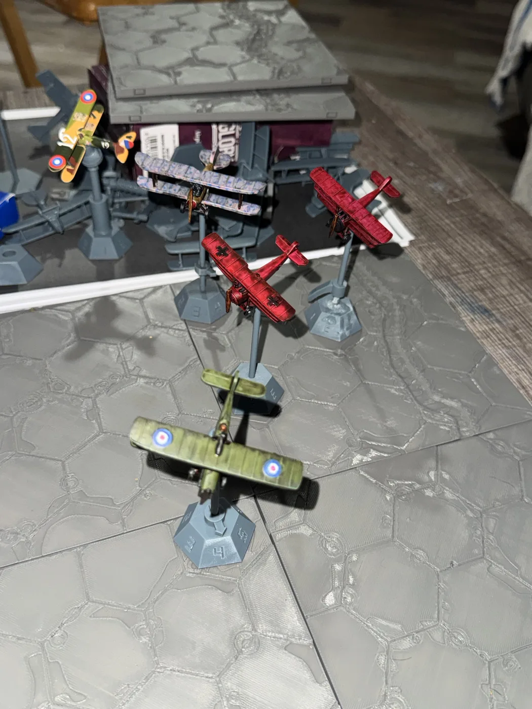 Painted and unpainted Death Spiral aircraft prototypes arranged over printed battlefield sections