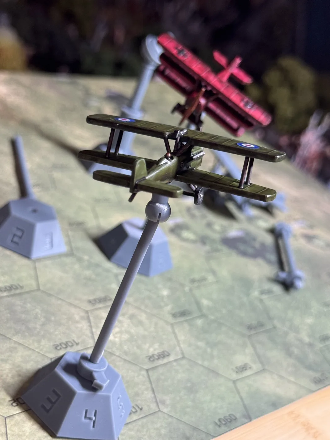 Close view of a painted green HexFlight biplane mounted on a numbered HexAxis stand